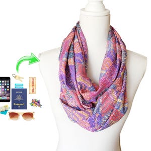 May include: A purple and pink infinity scarf with a colourful patterned design. The scarf is made of a soft, lightweight fabric and is perfect for adding a pop of colour to any outfit.