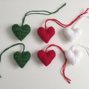 May include: Six knitted heart ornaments in green, red, and white, each with a matching string for hanging. The green and red hearts have a sparkly thread woven in. These heart-shaped decorations are perfect for Valentine's Day or other celebrations.