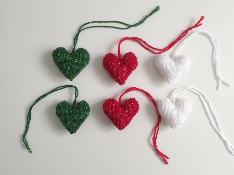 May include: Six knitted heart ornaments in green, red, and white, each with a matching string for hanging. The green and red hearts have a sparkly thread woven in. These heart-shaped decorations are perfect for Valentine's Day or other celebrations.