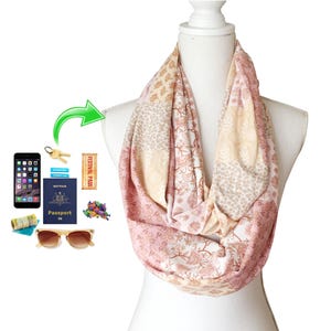 Puede incluir: Una bufanda infinita rosa y beige con un patrón floral y geométrico. La bufanda está doblada y se muestra en un maniquí blanco.