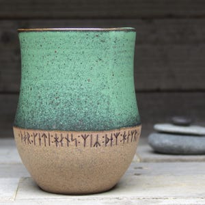 a green and brown vase sitting on top of a table