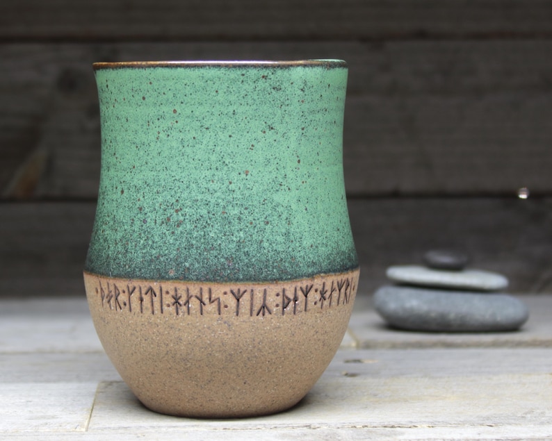 a green and brown vase sitting on top of a table