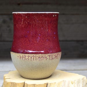 a red and white vase sitting on top of a wooden stump