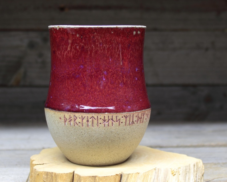 a red and white vase sitting on top of a wooden stump
