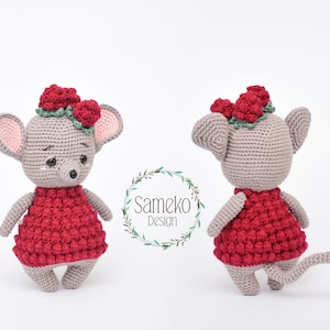 Pode incluir: Um rato cinzento de crochê usando um vestido vermelho e uma coroa de flores vermelhas. O rato tem orelhas grandes com o interior rosa, um pequeno nariz preto e olhos pretos. A imagem inclui o texto "Sameko Design".