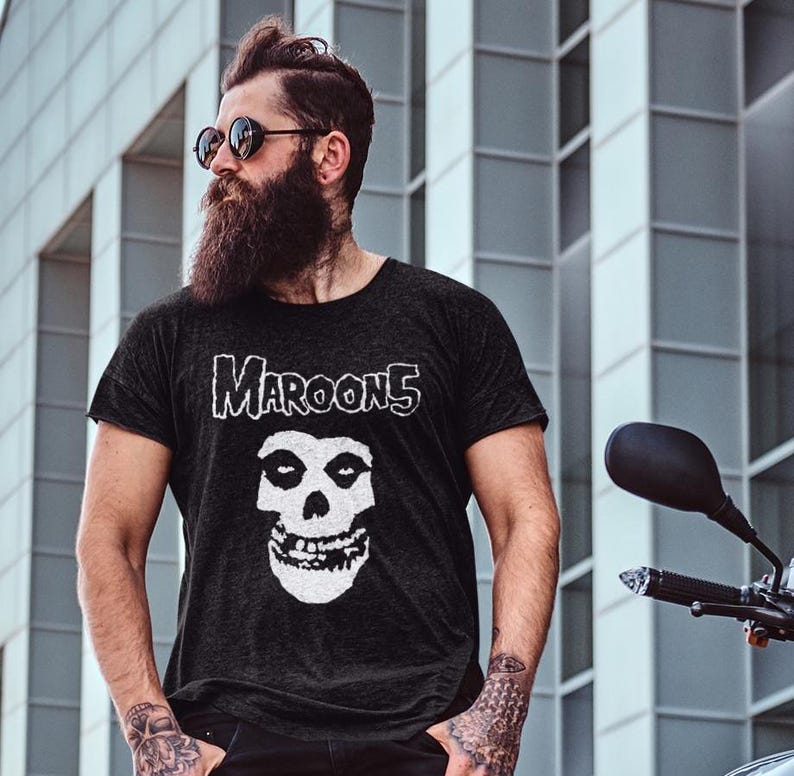 K&ouml;nnte beinhalten: Ein schwarzes T-Shirt mit einem wei&szlig;en Grafikdruck eines Sch&auml;dels und dem Text "Maroon 5" auf der Vorderseite.