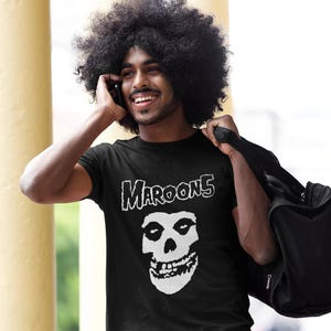 K&ouml;nnte beinhalten: Ein schwarzes T-Shirt mit einem wei&szlig;en Grafikdruck eines Sch&auml;dels und dem Text "Maroon 5" auf der Vorderseite.