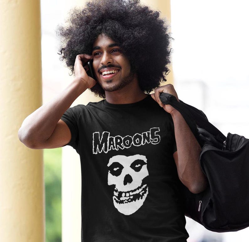 K&ouml;nnte beinhalten: Ein schwarzes T-Shirt mit einem wei&szlig;en Grafikdruck eines Sch&auml;dels und dem Text "Maroon 5" auf der Vorderseite.