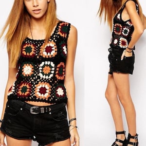 May include: A sleeveless crochet top with a geometric pattern in shades of orange, red, green, white, and black. The top is worn with black denim shorts.