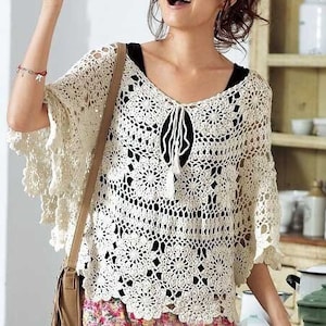 May include: A white crocheted top with a delicate floral pattern and a tie at the neckline. The top has a loose, flowing fit and is perfect for a summer day.