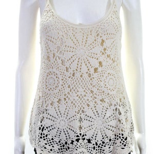 May include: A white crochet tank top with a scalloped hem. The top is made of a delicate, open-weave fabric with a floral pattern.