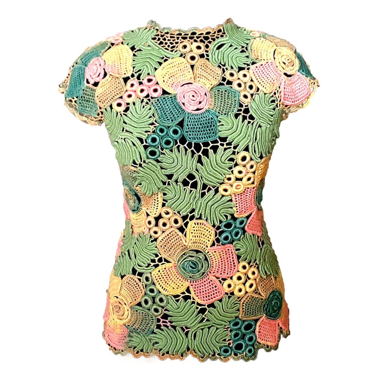 May include: A crocheted top with a floral design in shades of green, yellow, pink, and peach. The top has short sleeves and a round neckline.
