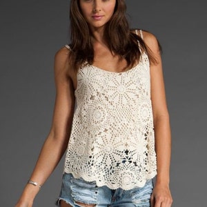 May include: A white crochet tank top with a delicate floral pattern. The top has a loose fit and a scalloped hem.