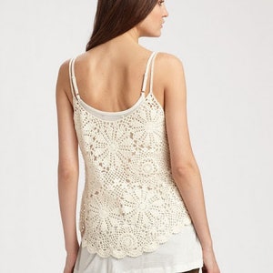 May include: A white crochet tank top with a layered look. The top has a delicate crochet pattern and a relaxed fit.