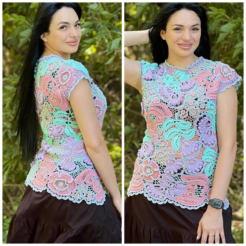 May include: A crocheted top with a floral design in shades of pink, purple, and green. The top has short sleeves and a round neckline.
