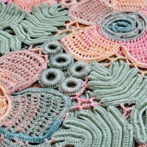 May include: Close-up of a crocheted doily with a variety of pastel colors, including pink, green, and blue. The doily is made up of several different patterns, including circles, flowers, and leaves.