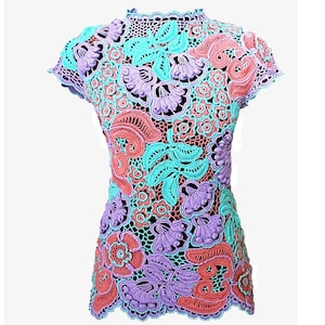 May include: A crocheted top with a floral design in shades of pink, purple, and turquoise.