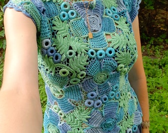 May include: A crocheted top with a floral design in shades of green and blue. The top is sleeveless and has a round neckline.