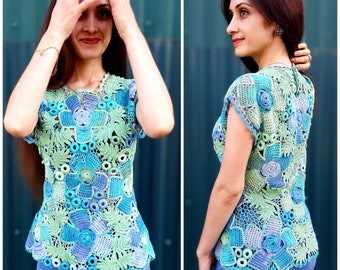 May include: A crocheted top with a floral design in shades of blue, green, and white. The top has short sleeves and a fitted silhouette.