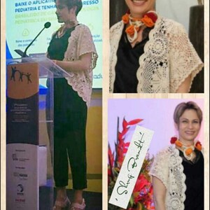 May include: A woman wearing a white crocheted shrug over a black top and black pants. She is standing at a podium and speaking. The text on the podium reads "Pediatrica". The image also includes a close-up of the woman wearing the shrug and a bouquet of flowers with a handwritten note that reads "Shrug Brandt".