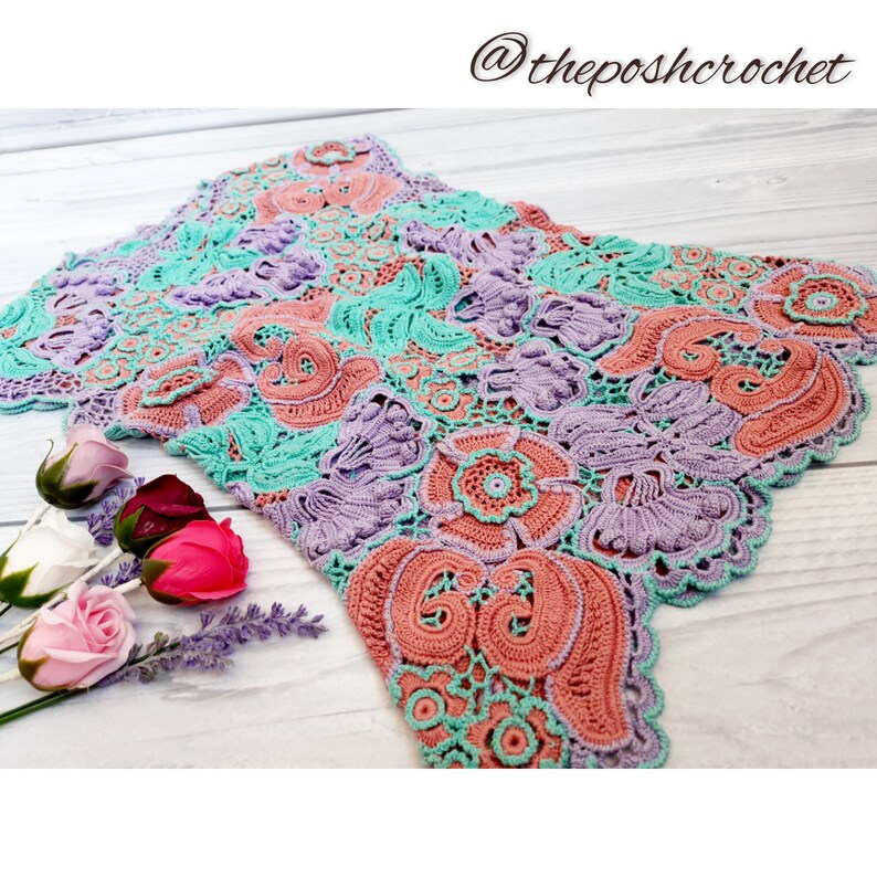 May include: A crocheted lace doily in shades of pink, purple, and green. The doily has a scalloped edge and intricate floral designs.