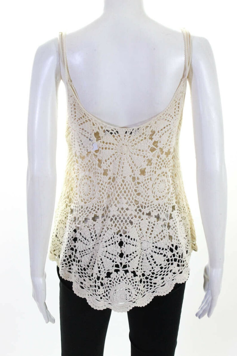 May include: A white crochet tank top with a delicate, intricate pattern. The top has a scoop neck and thin straps.