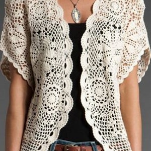 May include: A white crochet cardigan with a delicate floral pattern and short sleeves.