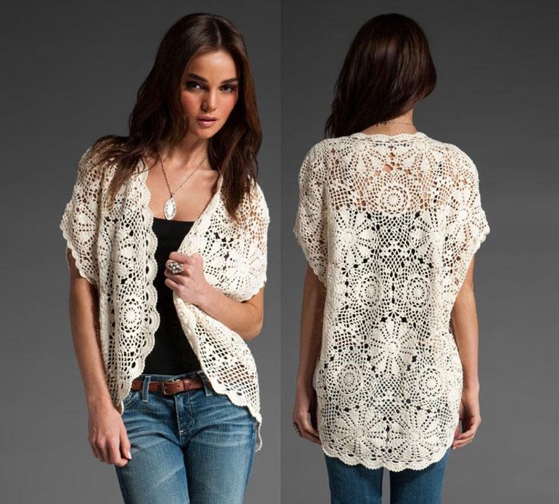 May include: A white crocheted cardigan with a delicate openwork pattern. The cardigan has a V-neck and short sleeves.