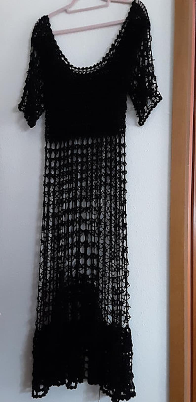 Puede incluir: Un vestido negro de crochet con un corte holgado y un dobladillo festoneado. El vestido est&aacute; hecho de una tela ligera y transpirable y tiene un estilo relajado y bohemio.