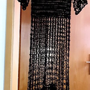 Puede incluir: Un vestido maxi de crochet negro de corte holgado y bajo festoneado.
