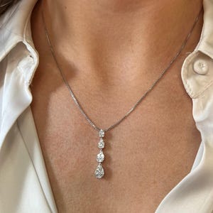 Puede incluir: Un collar de cadena de plata con un colgante que presenta cuatro grupos de diamantes en forma de l&aacute;grima.