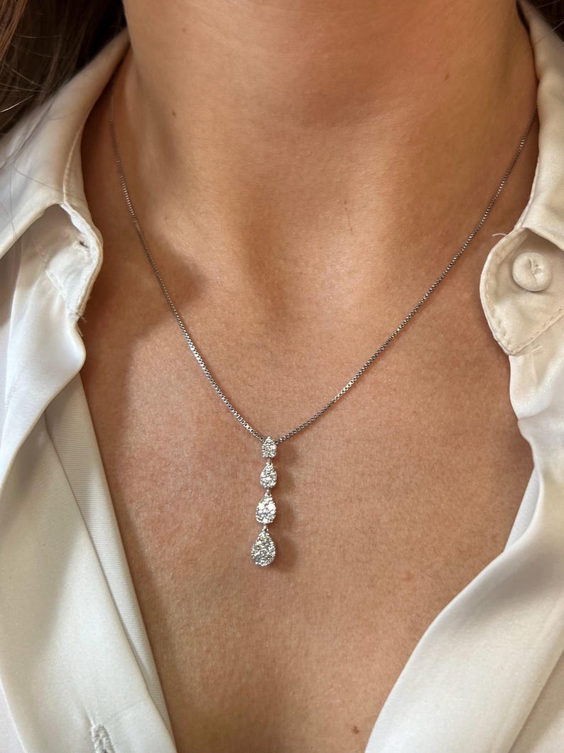 Puede incluir: Un collar de cadena de plata con un colgante que presenta cuatro grupos de diamantes en forma de l&aacute;grima.