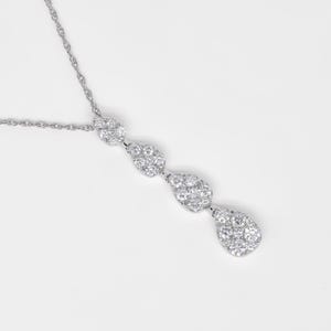 Puede incluir: Un collar de plata con una cadena delicada y cuatro colgantes en forma de l&aacute;grima, cada uno adornado con piedras de circonita c&uacute;bica brillantes.