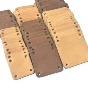 May include: A large stack of brown and beige leather patches with four holes each. The patches are all the same size and shape.