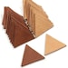 May include: A stack of brown leather triangles and a stack of tan leather triangles. There are two individual triangles, one brown and one tan, on a white surface.