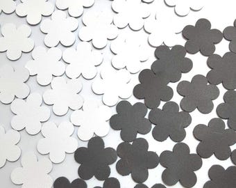 May include: A collection of white and black felt flower shapes. The flowers are all the same size and shape, and they are arranged in a random pattern.