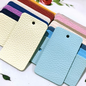 May include: A stack of leather samples in various colors, including cream, light blue, pink, beige, and brown. The samples are arranged in a fan shape and have a textured surface.