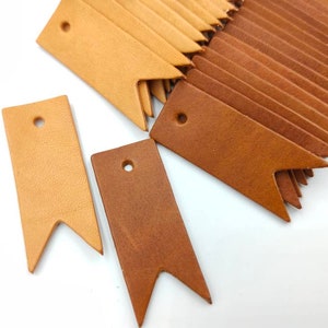 May include: A set of leather tags with a pointed end and a hole for string. The tags are in two shades of brown, one light and one darker.