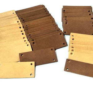May include: A large stack of brown and beige leather labels with holes punched in them. The labels are rectangular and have a rough texture.