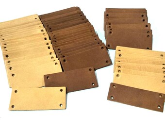 May include: A large stack of brown and beige leather labels with holes punched in them. The labels are rectangular and have a rough texture.