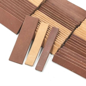 May include: A stack of brown and beige rectangular tiles. The tiles are arranged in a staggered pattern, with the brown tiles on top of the beige tiles.