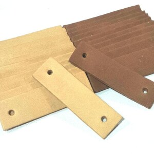 May include: Two sets of leather straps, one set is brown and the other is beige. Each strap has two holes punched through it.