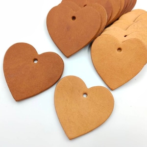 May include: A stack of brown leather heart-shaped tags with a hole punched in the top.