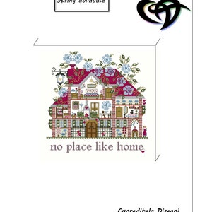 Peut inclure: Une broderie au point de croix représentant une maison de poupée avec un toit rouge et des murs en briques, ornée de fleurs bleues. Le texte "Spring dollhouse" et "no place like home" sont inclus. Le nom de l'artiste est également visible.