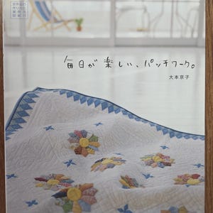May include: A book cover showing a patchwork quilt with colourful floral patterns. The quilt is white with blue edging and accents. Japanese text is visible, including the title "Everyday is fun, patchwork."