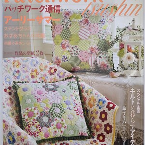 May include: A quilting magazine cover, "Patchwork Tsushin," displays two cushions with floral and geometric designs. The cushions are placed on a floral patterned chair and a table with a white lace tablecloth. The magazine title is in English and Japanese.