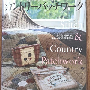 May include: A book with Japanese text and the English title "Stitch & Country Patchwork." The cover displays a patchwork quilt and two small fabric pouches. One pouch has a flower design, the other reads "It's My Relax Time." A window is in the background.