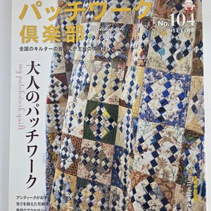 May include: A magazine cover with Japanese text and a patchwork quilt design. The title reads "Patchwork Club" with the number "104" and the date "2014.11". The quilt is made of various patterned fabrics in blue, beige, and brown.
