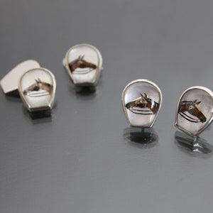 May include: A set of four silver cufflinks with a white background and a brown horse head design.