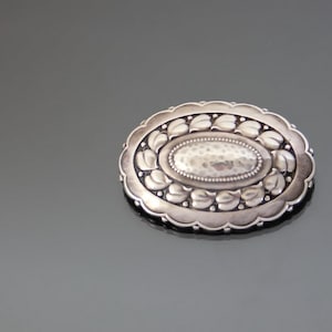 FALK BROTHERS. Spilla vintage in stile Arts and Crafts, in argento 800 sbalzato e martellato.